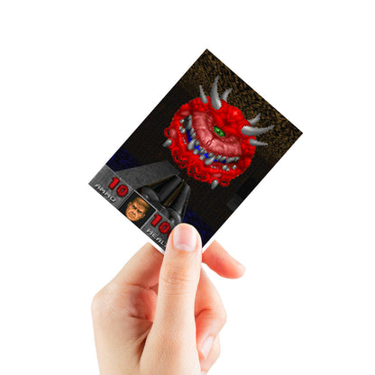 A hand holding a DOOM Cacodemons Apex Deck Protector sleeve featuring a pixelated Cac demon and game HUD elements.