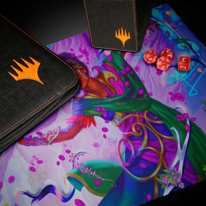 A black Magic: The Gathering deck box and binder with orange Magic: The Gathering logos, placed on a playmat featuring the Aetherdrift Avishkar Living Energy artwork. Three red dice are also visible on the playmat. Brand: Magic: The Gathering, Item: Aetherdrift Avishkar Living Energy (Commander) Playmat.
